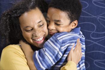 A mid adult African American woman affectionately hugging her young son. Horizontal shot.