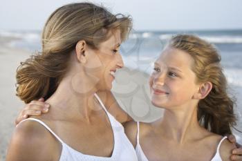 Mother and daughter smile with arms around one another. Horizontal shot.