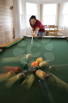 Man shooting game of pool with balls scattering after hit.