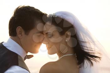 Backlit image of a newlywed couple on the beach. Horizontal shot.