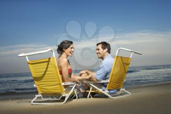 Man and woman sit in beach chairs and enjoy one another's company. Horizontal shot.