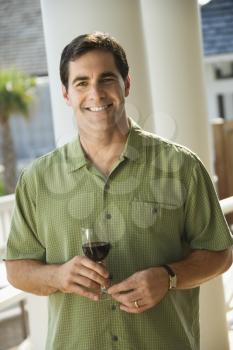 Portrait of smiling man standing outside with glass of red wine. Vertical shot.