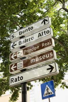 Low angle view of pedestrian crossing sign and directional signs in Lisbon, Portugal. Vertical shot.
