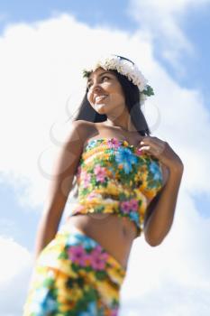 Portrait of attractive young Hawaiian woman in tropical flower print summer attire smiling with a lei on her head.