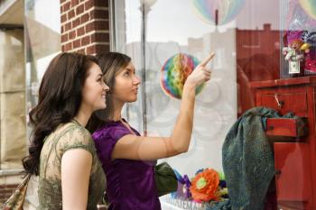 Young women pointing to items in an interior design store window. Horizontal shot.