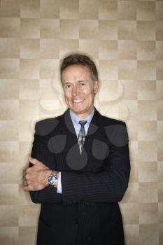 Portrait of a Caucasian middle-aged businessman wearing a suit and smiling at the camera. Vertical format.