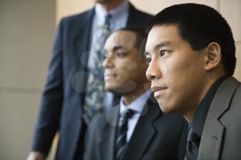 Asian businessman in the foreground with African-American businessman and a third businessman in the background. Horizontal format.