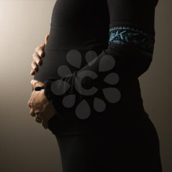 Closeup profile of the torso of a pregnant woman. Square shot. Isolated on gradient brown.