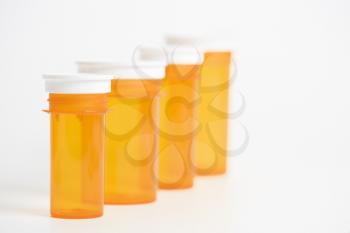 Yellow medicine bottles in diminishing sizes lined up. Horizontal shot. Isolated on white.
