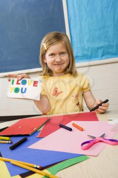 Young girl showing card made in art class that says I love you.