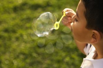 Young boy blowing bubbles outside. Horizontally framed shot.
