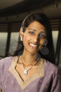 Portrait of an attractive young Indian woman wearing traditional clothing and smiling at the camera. Vertical shot.
