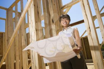 Woman holding blueprints on construction site. Horizontally framed shot.
