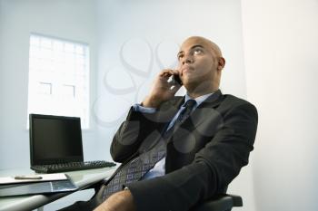 African American businessman holding cellphone to ear looking bored.