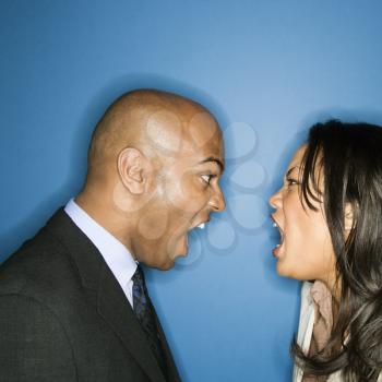 Businessman and businesswoman face to face yelling at eachother.