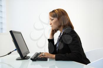 Portrait of African American businesswoman sitting at office desk working on computer.