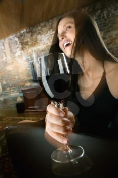Pretty young Caucasian woman toasting wine glass and laughing.