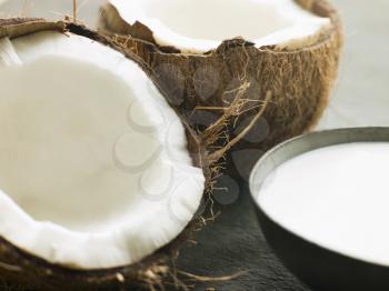 Royalty Free Photo of a Dish of Coconut Milk with a Split Fresh Coconut