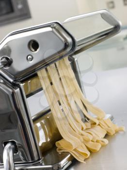 Royalty Free Photo of Fresh Egg Tagliatelle Being Rolled in a Pasta Machine