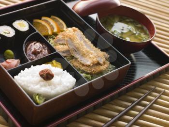 Royalty Free Photo of a Tonkatsu Box and Miso Soup with Pickles and Sushi
