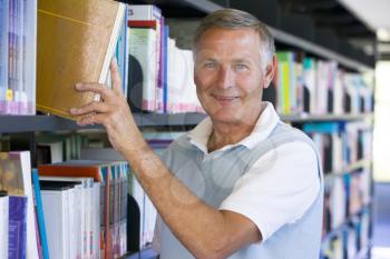 Royalty Free Photo of a Man Taking a Book Off a Shelf