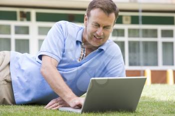 Royalty Free Photo of a Man Lying on a Lawn With a Laptop