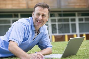 Royalty Free Photo of a Man Lying on the Lawn With a Laptop