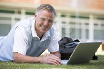 Royalty Free Photo of a Man Lying on the Lawn With a Laptop
