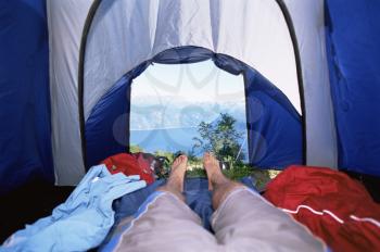 Royalty Free Photo of a Men's Legs in a Tent Overlooking Hills