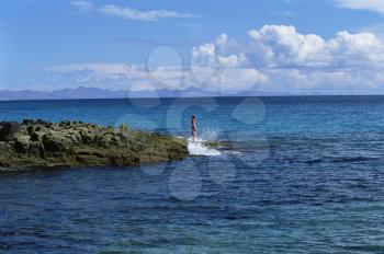 Royalty Free Photo of a Woman Standing on Large Rocks at the Edge of an Ocean