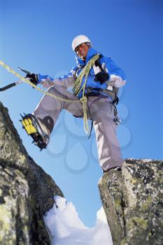 Royalty Free Photo of a Mountain Climber Stepping Over a Crevasse