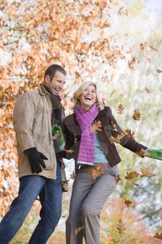 Royalty Free Photo of a Couple Throwing Autumn Leaves