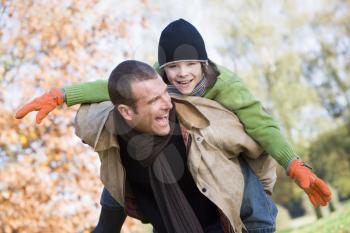 Royalty Free Photo of a Father and Son Piggybacking Outside