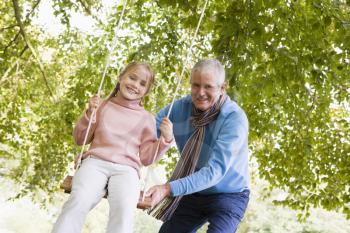 Royalty Free Photo of a Grandfather Pushing a Little Girl on a Swing