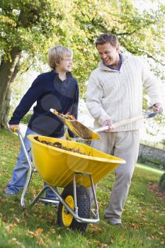 Royalty Free Photo of a Father and Son Shovelling Leaves