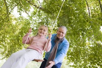 Royalty Free Photo of a Man Pushing a Girl on a Swing