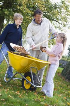 Royalty Free Photo of a Father Getting Help From Two Children Raking the Lawn