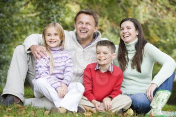 Family sitting outdoors in park smiling (selective focus)