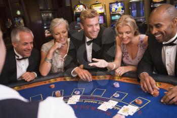 Five people in casino playing blackjack and smiling (selective focus)