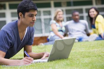 Royalty Free Photo of a Student Working on a Laptop With Other People in the Background