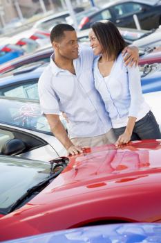 Royalty Free Photo of a Couple Looking at Each Other While Shopping for Cars