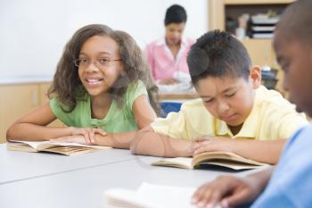 Royalty Free Photo of Students Reading in Class With a Teacher in the Background