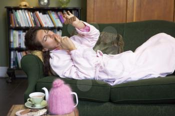 Royalty Free Photo of a Woman Lying on a Sofa Eating Chocolate