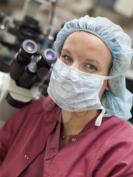 Royalty Free Photo of a Woman in a Surgical Mask Beside a Microscope