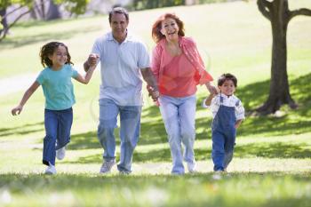 Royalty Free Photo of Grandparents Running in a Park With Grandchildren