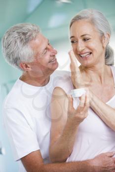 Royalty Free Photo of a Couple Standing Close With the Woman Holding Cream