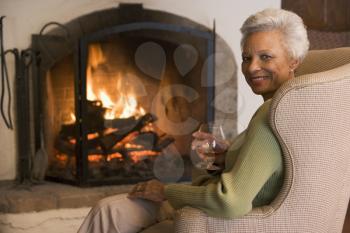 Royalty Free Photo of a Woman With a Drink Beside a Fireplace