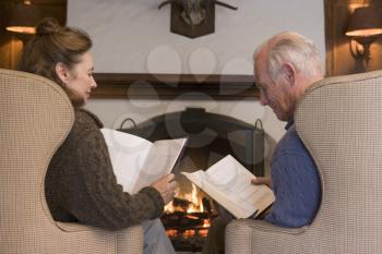 Royalty Free Photo of a Couple Reading Beside a Fireplace