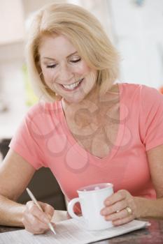 Royalty Free Photo of a Woman in the Kitchen With a Coffee and the Paper