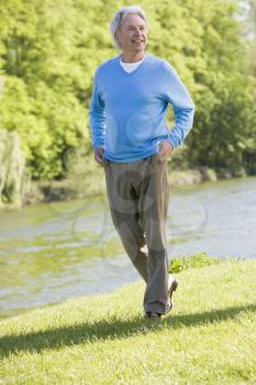 Royalty Free Photo of a Man Walking Beside a Stream